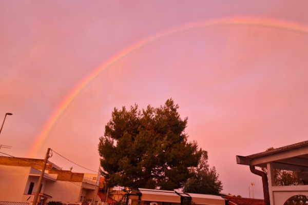 Raro arcobaleno all’alba con cielo rosa